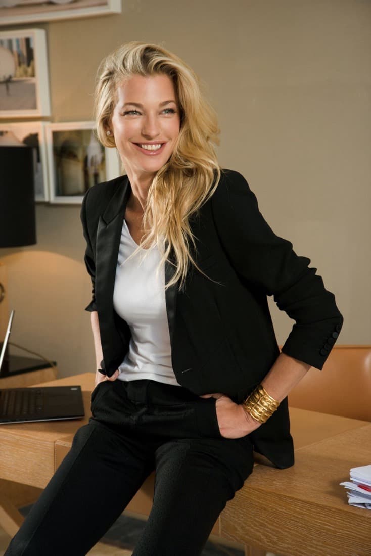 Nicole Junkermann, investor and entrepreneur, relaxed in a black blazer and white top, leaning on a desk